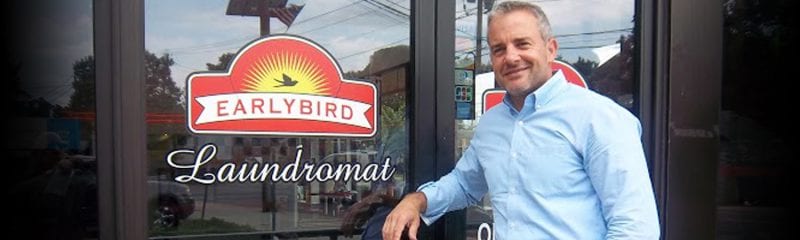 owner standing in front of door with logo