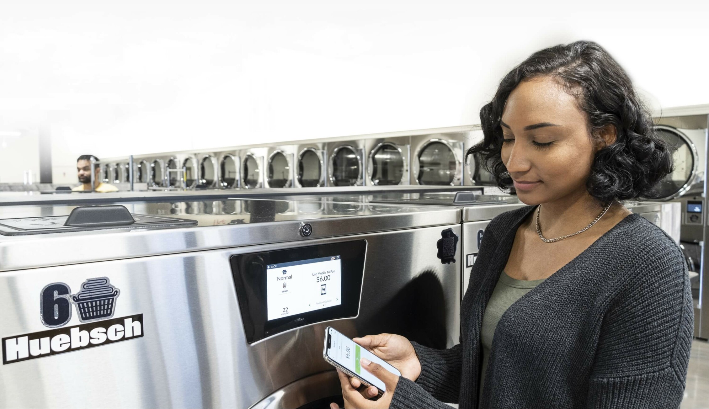 Woman using Huebsch technology on her phone to pay for laundry